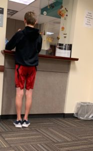 Teen standing at the doctors office check in desk. 